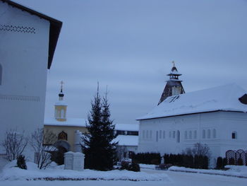 Church by building against sky during winter