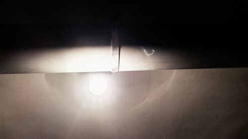 Low angle view of illuminated light bulb on wall