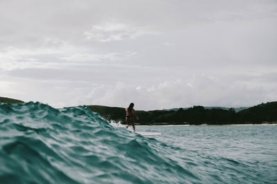 Man surfing in sea against sky