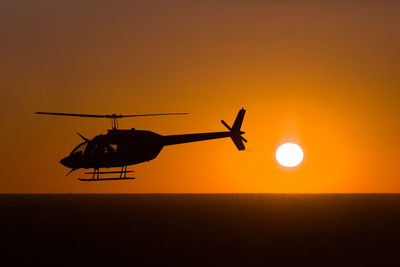 Helicopter flying on sunset background