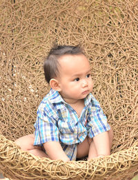 Cute boy looking away while sitting on chair