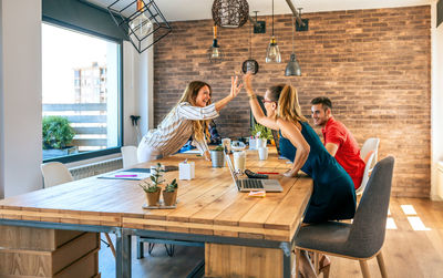 Business women celebrating a success high-fiving in the office