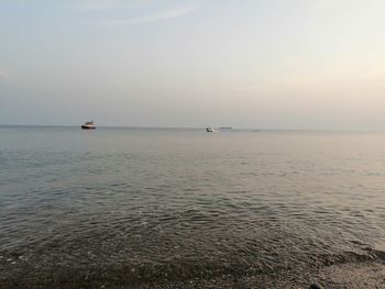 Sailboat sailing in sea against sky during sunset