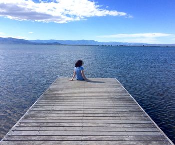 Rear view of woman on pier over sea against sky