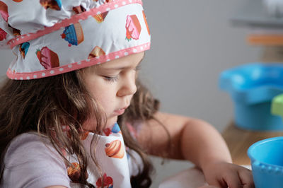 A young girl is playing chef at the kitchen table.