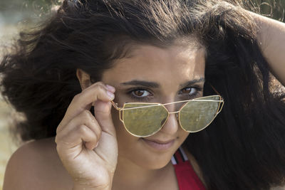 Close-up portrait of young woman holding sunglasses