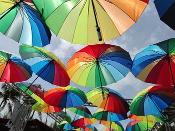 Low angle view of multi colored umbrellas hanging against sky