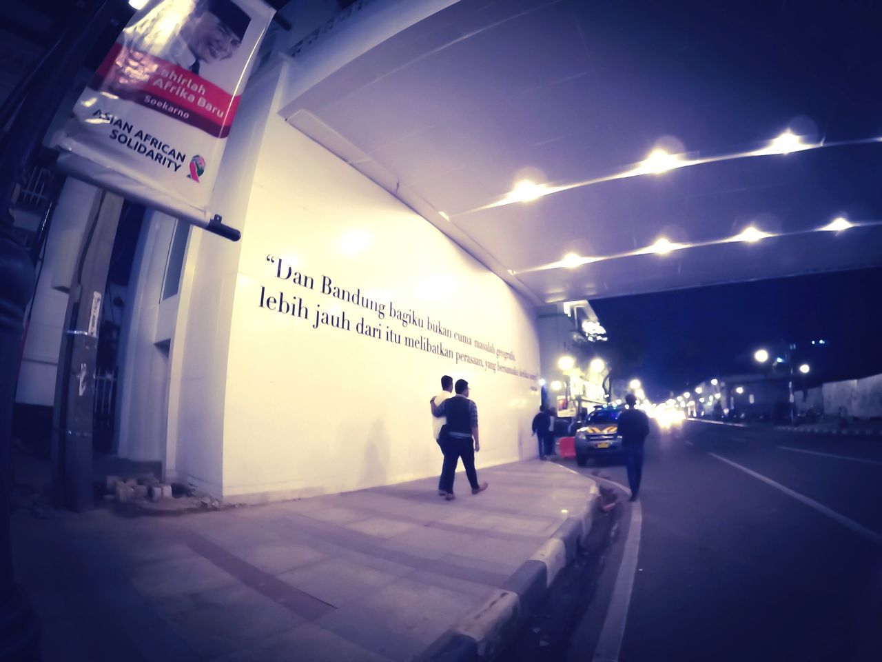 transportation, illuminated, walking, the way forward, built structure, architecture, text, road, full length, men, street, communication, lifestyles, road marking, night, city life, rear view, sky