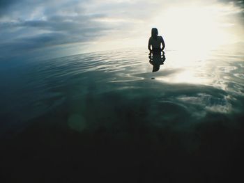 Silhouette woman in sea against sky