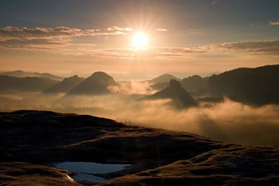 Distant mountain range and heavy clouds of colorful mist above deep valleys