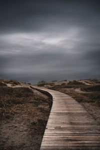 View of boardwalk on landscape against sky