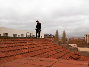 Man standing on roof against buildings in city