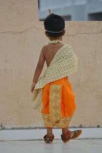 Rear view of girl standing against wall