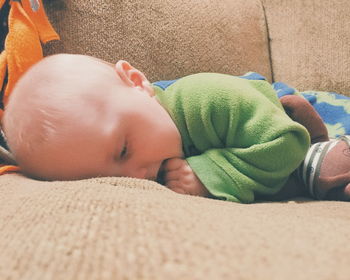 Close-up of cute baby boy lying on sofa at home