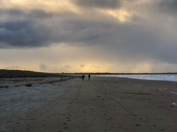 Silhouette man standing on beach against sky during sunset