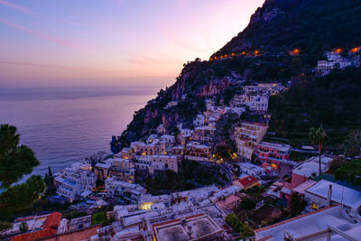 High angle view of townscape by sea against sky during sunset