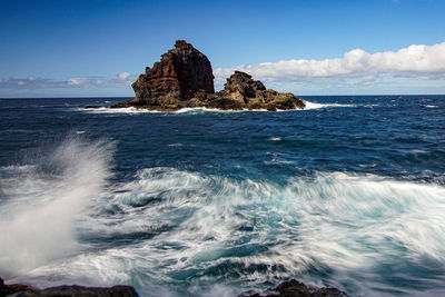 Scenic view of rocks in sea against sky