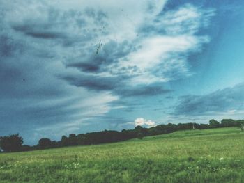Scenic view of grassy field against cloudy sky