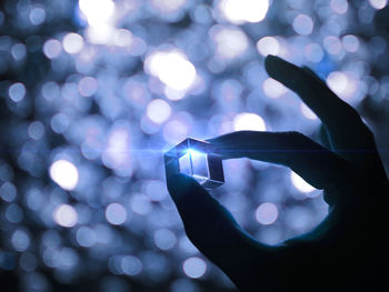 Close-up of silhouette hand holding illuminated light at night