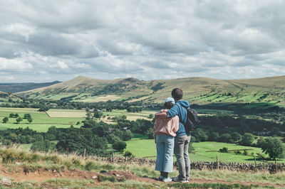 Rear view of man looking at landscape against cloudy sky