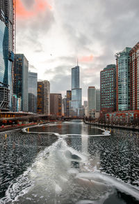 River amidst buildings in city against sky