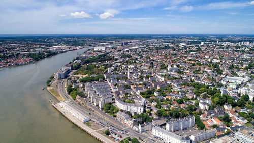 Aerial view of river and city buildings against blue sky