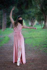 Teenage woman dancing ballet outdoors with protective face mask for protection from covid-19 virus