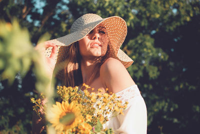 Beautiful young woman wearing hat against plants