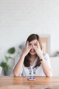 Portrait of smiling young woman sitting by table at home