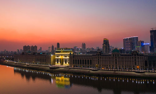 Illuminated buildings in city at sunset