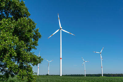 Five wind power turbines, part of a wind farm, on a green field near cottbus, brandenburg, germany.