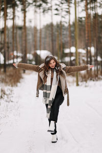 A funny pretty curly-haired girl in winter clothes is having fun walking alone in a snowy forest