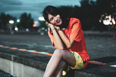 Portrait of smiling young woman sitting on road