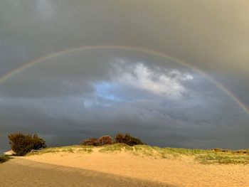Scenic view of rainbow over land against sky