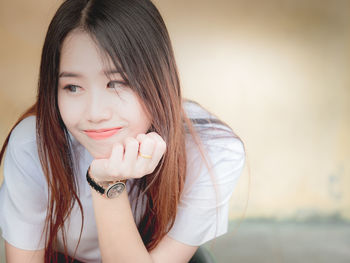 Close-up of smiling young woman looking away while sitting outdoors