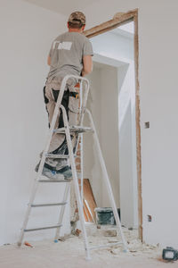 A young caucasian male builder clears a doorway using a crowbar.