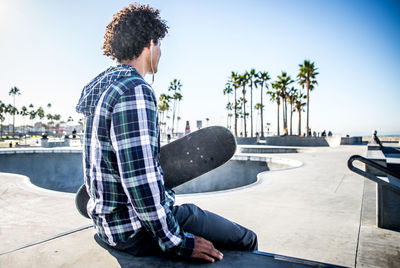 Man sitting in park against clear sky