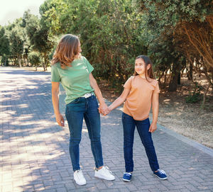 Full length of mother and daughter on footpath