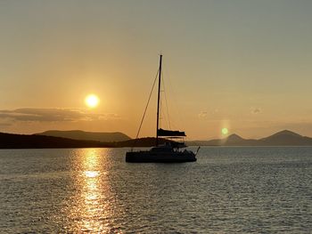 Sailboat sailing on sea against sky during sunset