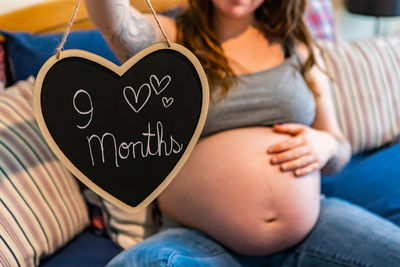 Midsection of woman making heart shape with text