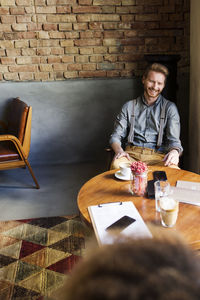 Happy businessman sitting at table in hotel lobby