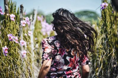 Rear view of woman running amidst plants in farm