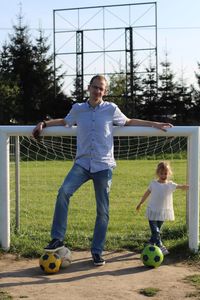 Portrait of father and daughter playing soccer on field