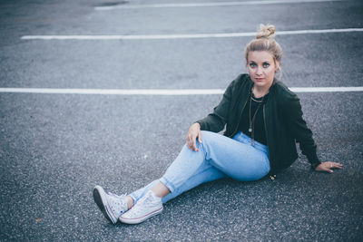 Portrait of young woman sitting on road