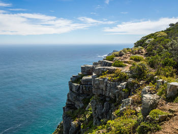 Scenic view of sea by cliff against sky