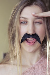 Portrait of a blonde woman wearing a fake mariachi mustache