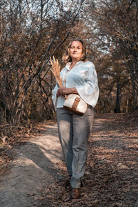 Portrait of smiling young woman standing in forest