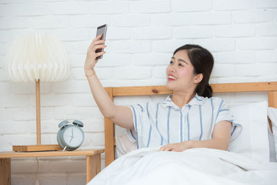 Young woman using mobile phone on bed