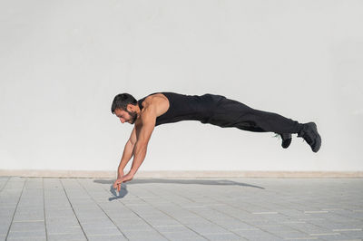 Side view of man exercising against wall