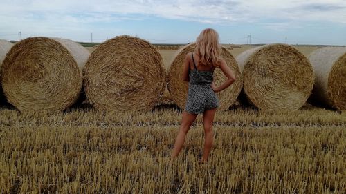 Rear view of woman with hay bales on field